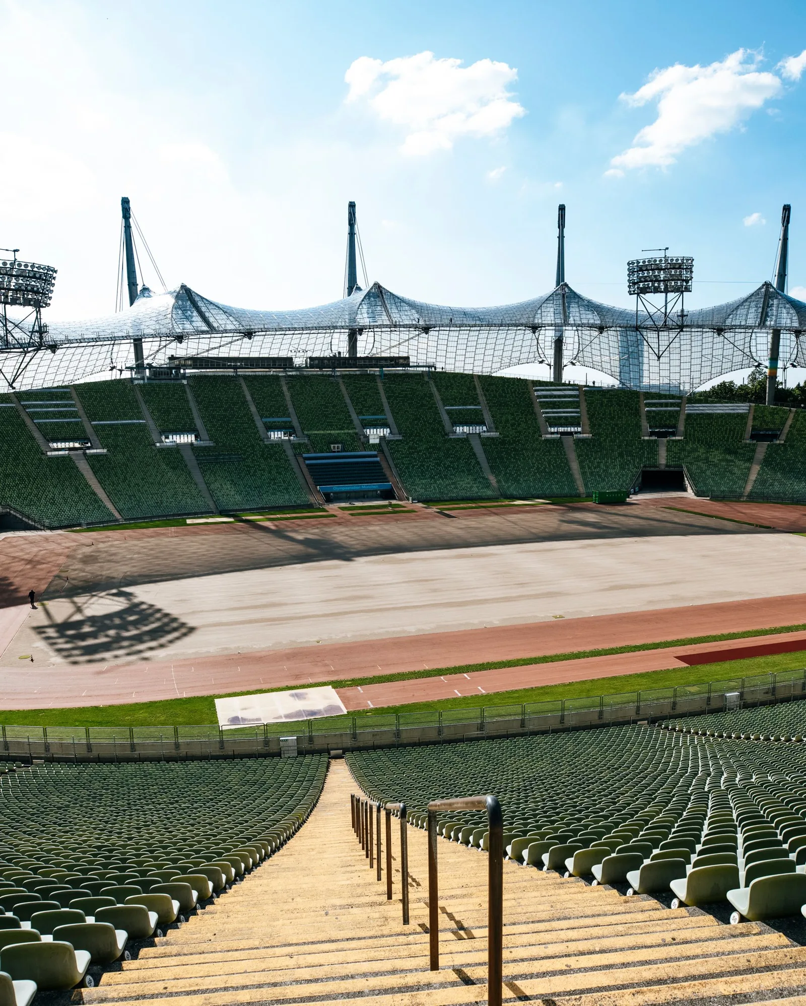 Grand stade vu en plan large depuis le haut d’une tribune vide, sous un ciel clair