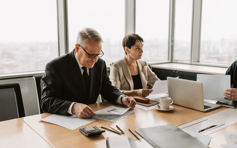 Cadres en réunion de travail autour d’une table, documents et ordinateur portable